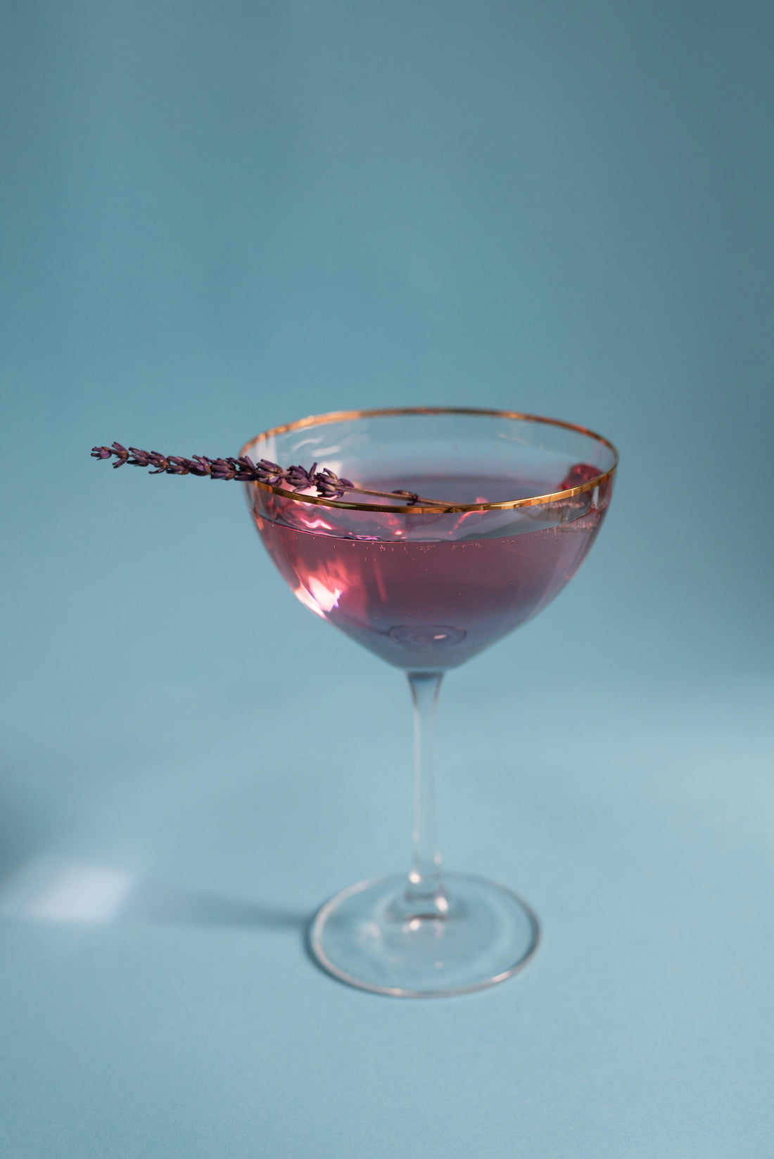 zero-proof cosmopolitan alternative with lavender garnish on a blue backdrop